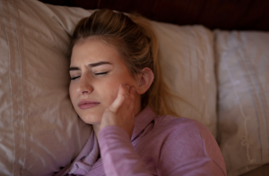 woman with jaw-pain-from-bruxisum-tmj-while-sleeping