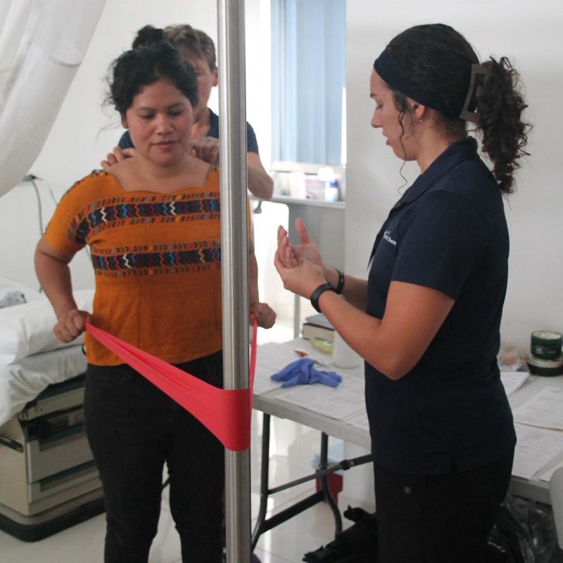 Amanda helps a patient in Guatemala with his exercises